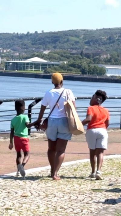A mother walking hand in hand with two children by the waterfront in Greenock