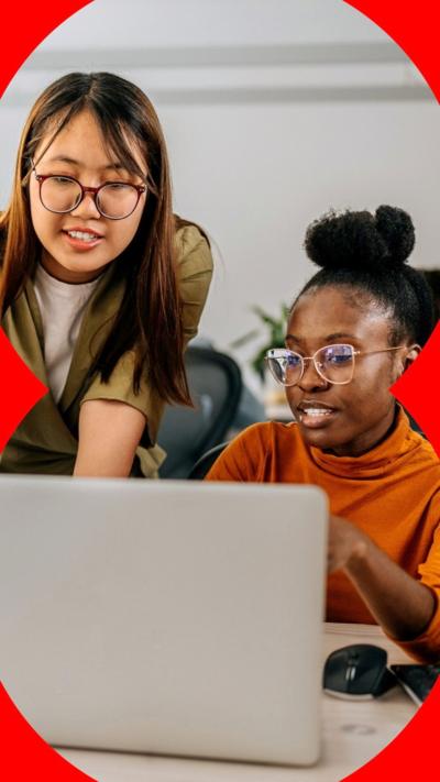 Two young women look at a laptop together