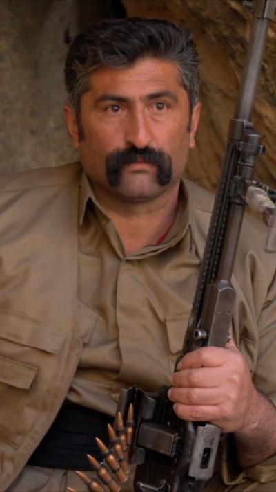 Kurdish fighter, with large moustache and a rifle with bullets visible