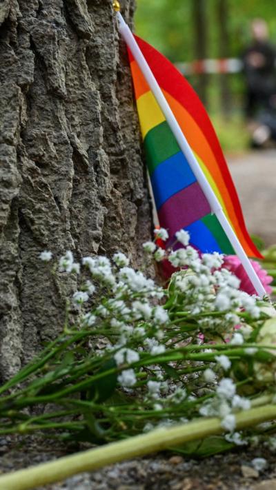 A vertical image of a pride flag and flowers