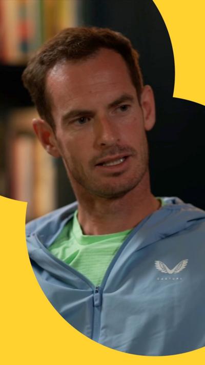 Andy Murray sits in front of a bookshelf, wearing a grey jacket