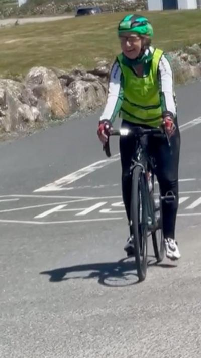 A woman on a bike cycling down a road.