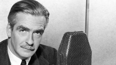 Anthony Eden sits behind a microphone