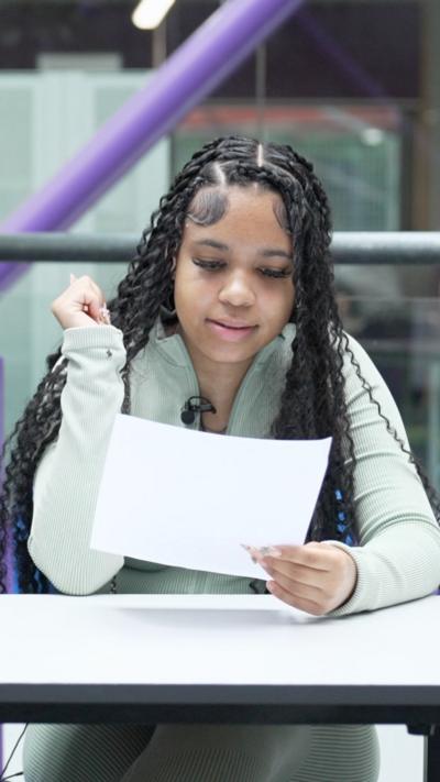 Student looks down at a piece of white paper in her hands