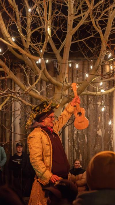 A person holding a ukulele with a top hat on at a Wassail