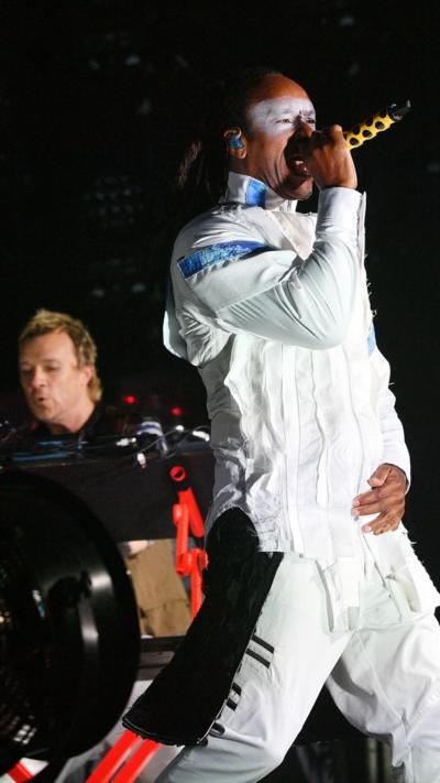 Maxim sings in a white boilersuit ith white facepaint with Liam Howlett in the background as The Prodigy perform at Glastonbury 2025