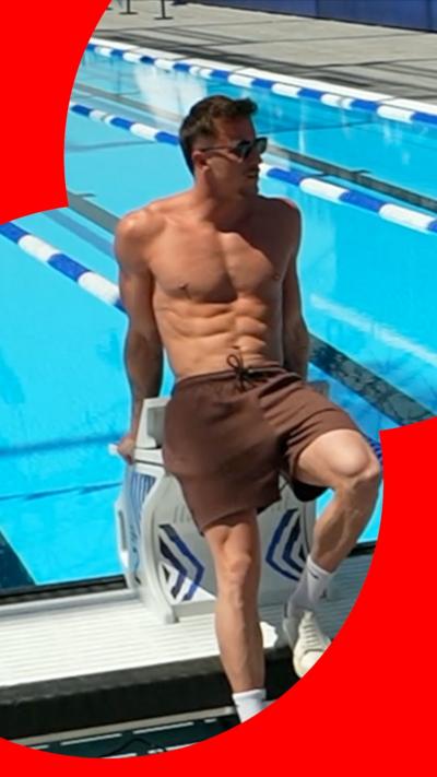 A male athlete poses for a picture in front of a pool