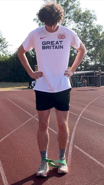 Man in a white Great Britain shirt looking down at his feet. 