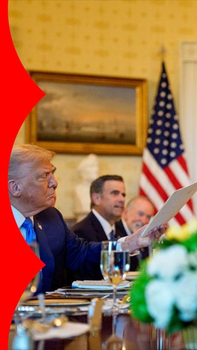 Donald Trump being handed a letter, with the US flag behind him.