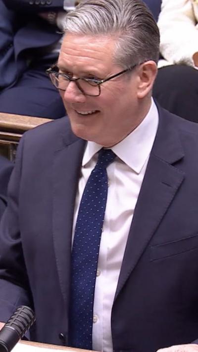 Keir Starmer smiling as he looks across at Kemi Badenoch 