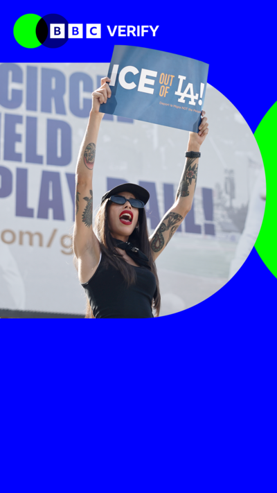 A women holds up a sign reading: "Ice out of LA." She is wearing sunglasses and is at a demonstration in Los Angeles. 