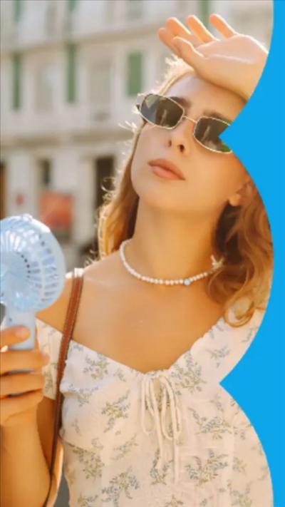 Woman with blonde hair. She's wearing sunglasses has her left hand on her forehead and a small electric fan in her right hand.