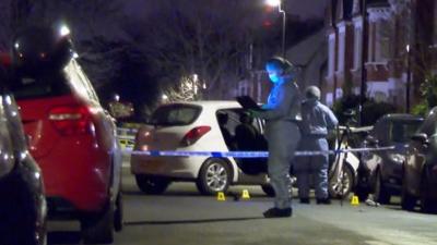 Forensics team standing next to cordoned-off car