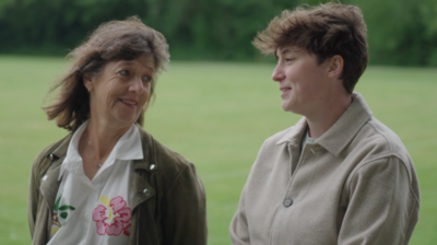 A mother and daughter stand in the middle of a field.