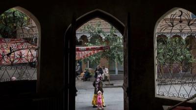 An Uighur woman walks by the closed Islamic school in Xinjiang