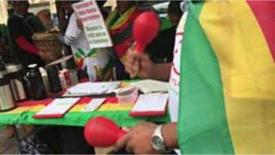 Man wearing Zimbabwean flag holding maracas