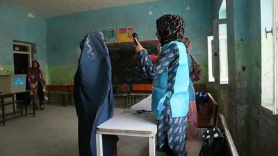 Afghan woman has her picture taken with a biometric reader as she prepares to cast her vote in Mazar-i-Sharif