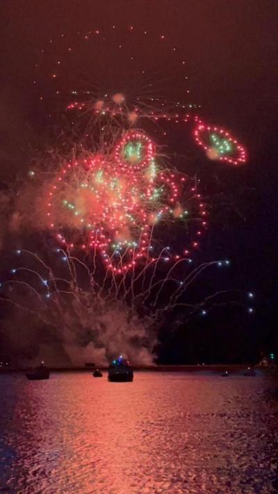 Red and green fireworks in the night sky over the sea. 