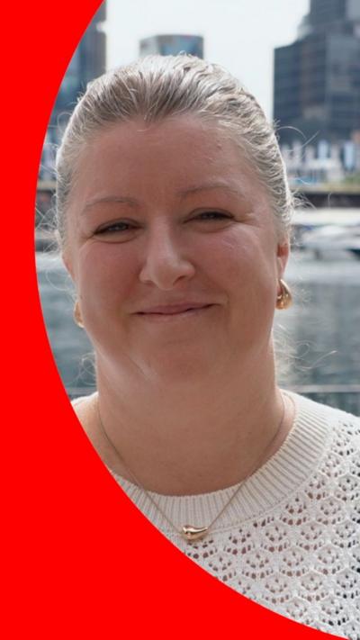 Woman wearing white crochet top smiles to camera