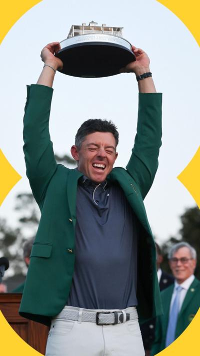 Rory McIlroy wears a green jacket while holding up the Masters trophy in 2025.