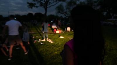 Nomia Iqbal in front of crowd of people in the darkness