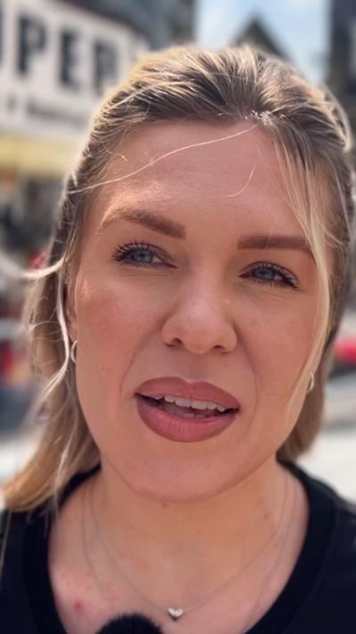 A woman with pulled back hair speaks into a microphone