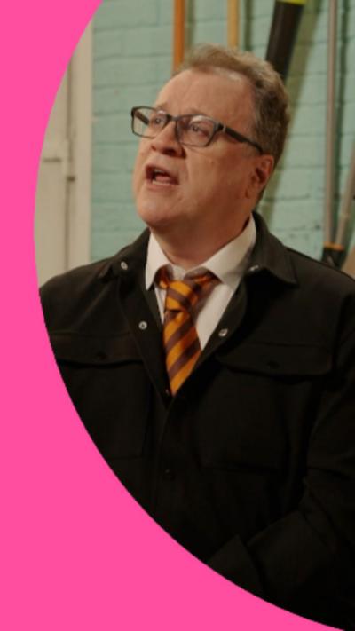 Russell T Davis is wearing glasses, an orange tie and a black jacket