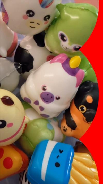 A collection of squishy toys including a white, pink and purple unicorn, and a blue carton of chips.