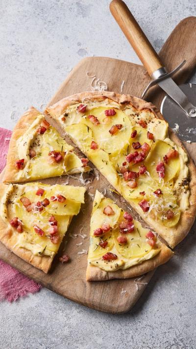 Top down view of a homemade sliced pizza on a wooden chopping board