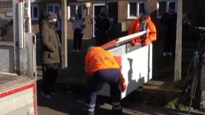 Two people in high-vis jackets take away the freezer