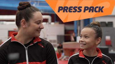 Two young gymnasts smiling at each other in their club, with the text PRESS PACK on the image.