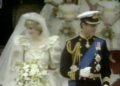 Prince Charles and Princess Diana standing arms interlocked in wedding clothes