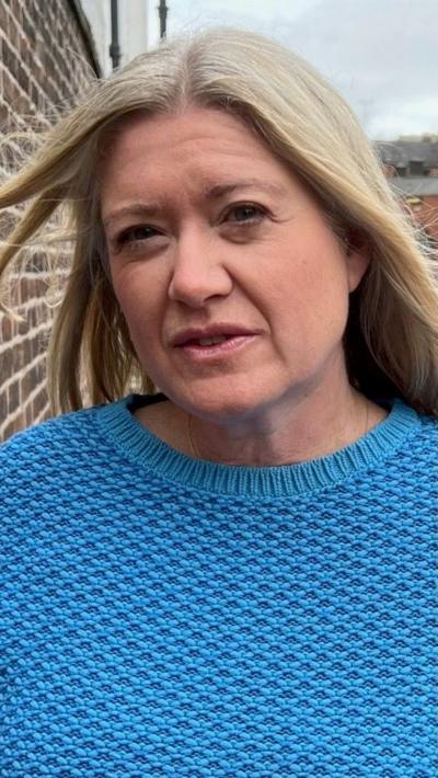 A woman with blonde hair wearing a light blue top