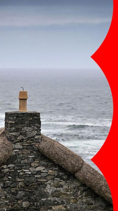 The top of a roof is visible with the sea in the background