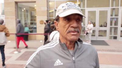 Kevin Williams wears a baseball cap and tracksuit top as he speaks outside an evacuation centre