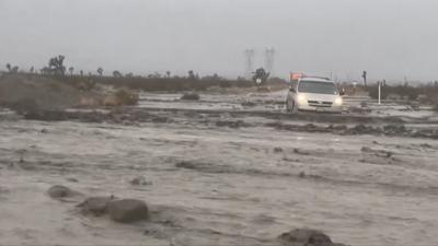 Muddy water is streaming down in California with a car seen.