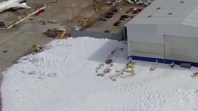 Fire suppression foam covers parking lot at a Houston hangar