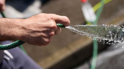 A man uses a hosepipe to clean a carpet in the street in Leeds