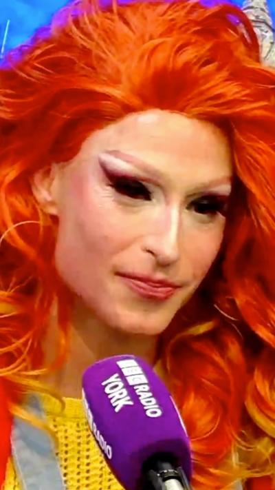 A drag queen speaks into a microphone