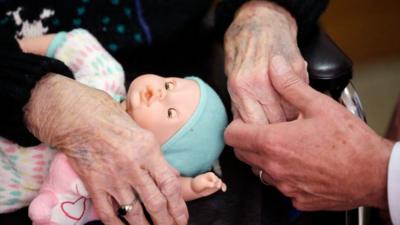 Two elderly people hold hands