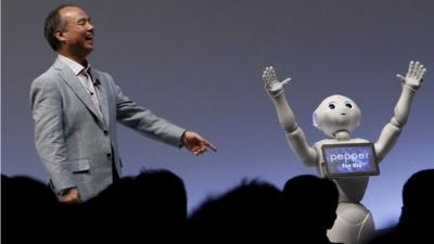 SoftBank Group Corp. Chairman and CEO Masayoshi Son reacts as SoftBank"s human-like robots named "Pepper" performs during the SoftBank World 2015 event in Tokyo
