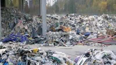 Piles of construction waste at a recycling plant in Finland. In the middle of the waste is heavy machinery