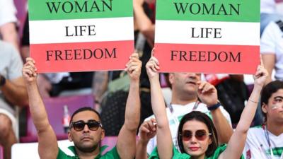 Two Iran fans holding up 'Women Life Freedom' banners