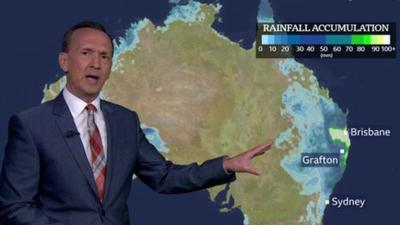 Weather presenter Nick Miller in front of a weather map of Australia with heavy rain on the east coast.