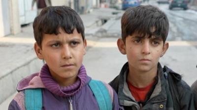 Two Afghan boys walk in the street in Kabul