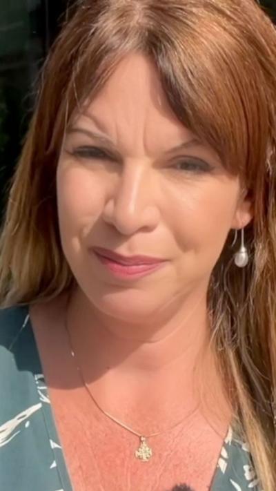 A woman with long, brown hair looks at the camera