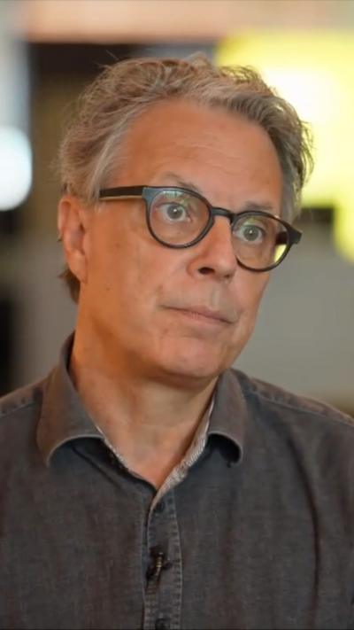 Close-up of Ian Russell, wearing grey shirt and glasses, during interview