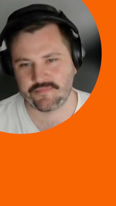A man, Ewan Valentine, wearing headphones and a white top 