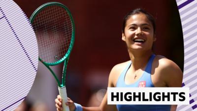 Emma Raducanu smiling and holding racket up