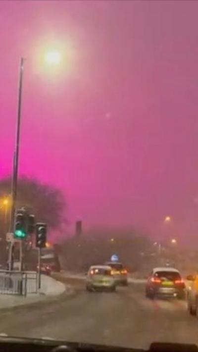 A pink sky above a snowy main road
